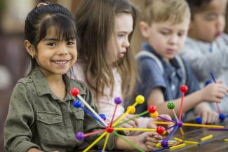 child smiling and looking towards the camera while holding a toy